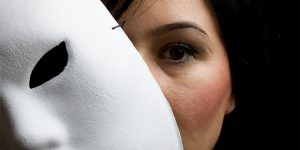 Woman With Black Hair And Eyes Peeking Behind White Mask