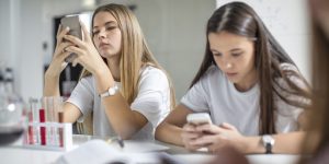 Teenage girls using cell phones in science class