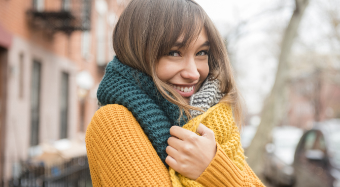 Portrait of smiling Mixed Race woman wearing scarf in city
